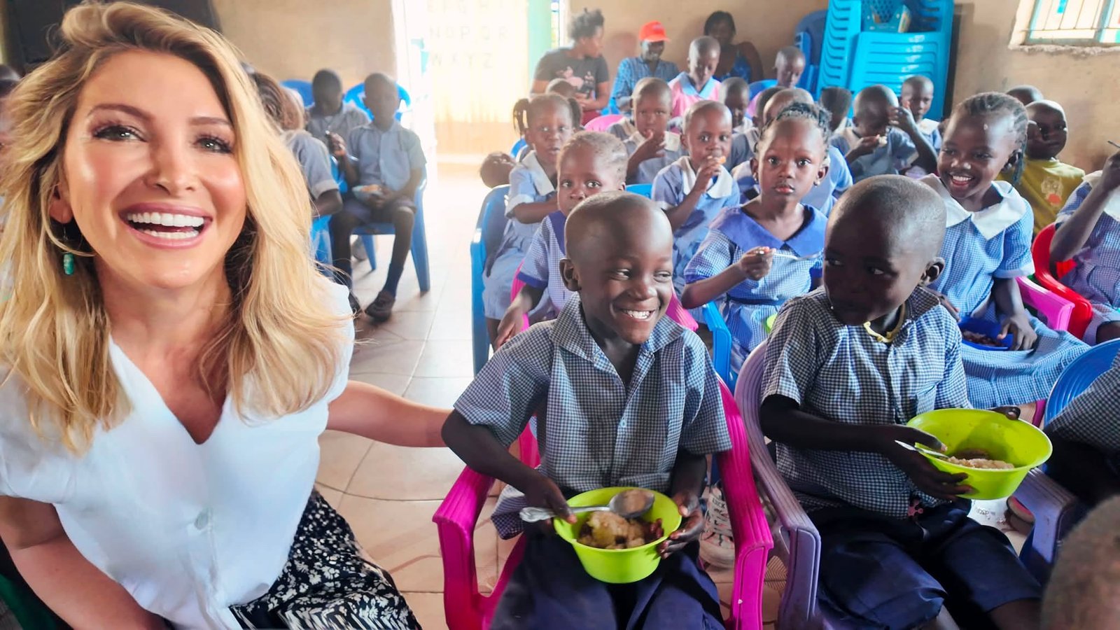 Founder Staci Austin with smiling schoolchildren sharing a meal in Kenya